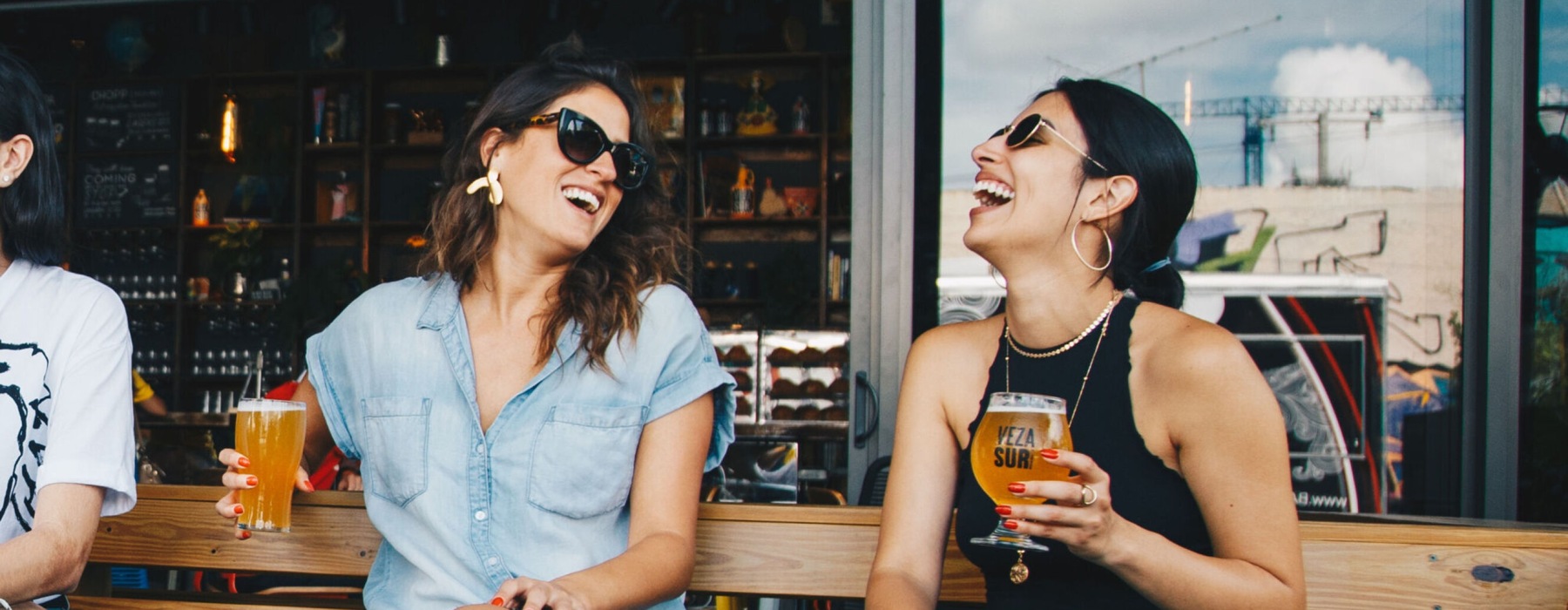 women laughing while holding drinks